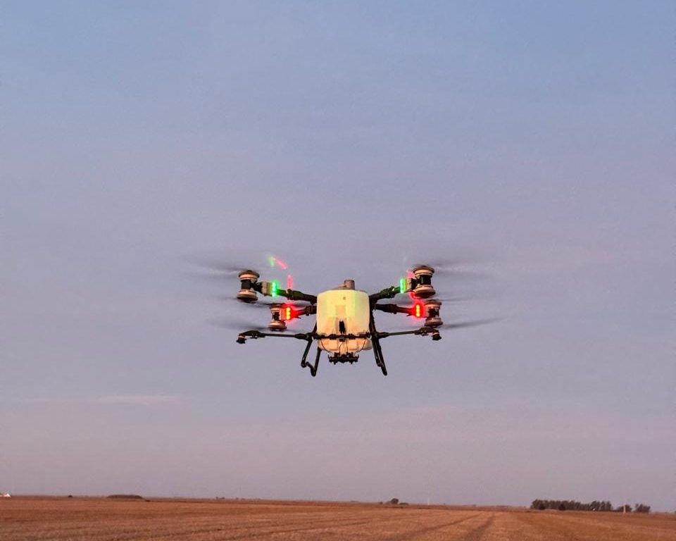 Dron DJI Agras volando sobre un lote al atardecer